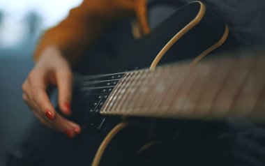 Evde yarı akustik gitar çalan bir kız..