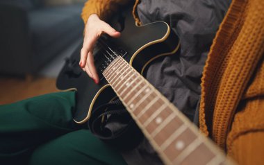 Evde yarı akustik gitar çalan bir kız..