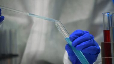 Laboratuvarda deney tüpleri ve petri kabıyla çalışan bir bilim adamı..