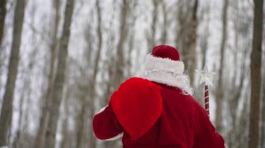 Sihirli değnekli Noel Baba ve kar ormanında bir çanta dolusu Noel hediyesi. Arka plan.