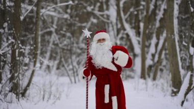 Sihirli değnekli ve Noel hediyeli Noel Baba kar ormanlarında yürüyor..