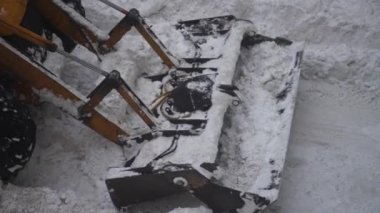 Sokakta kar kürekle traktör.