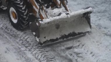 Sokakta kar kürekle traktör.