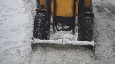 Sokakta kar kürekle traktör.