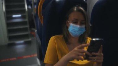 Tıbbi maskeli kadın trenin içinde seyahat ediyor..