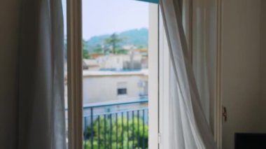 Kadın pencerenin önünde dururken yaz melteminin tadını çıkarıyor..