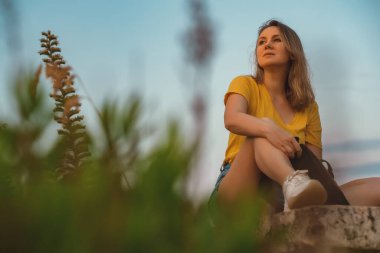 Woman tourist with backpack resting at sunset.