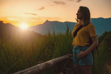 Woman tourist with backpack visits the nature reserve park.