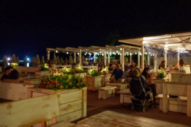 People have dinner in a restaurant in the evening. Blurred image.