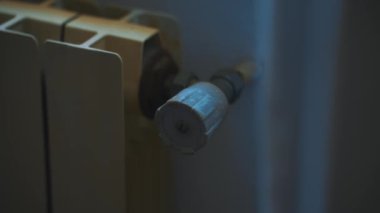 Woman turning down heating thermostat on the radiator to save money.