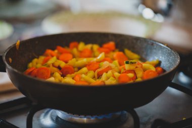 Zucchini with carrots and onions frying in pan.