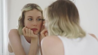 Teenage girl doing makeup with black eyeliner.