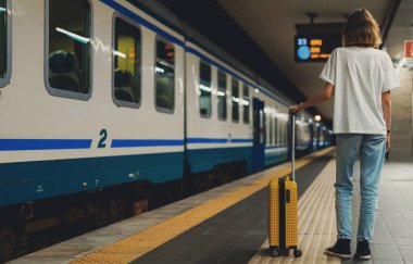 Teenage girl with a suitcase waiting for the train.