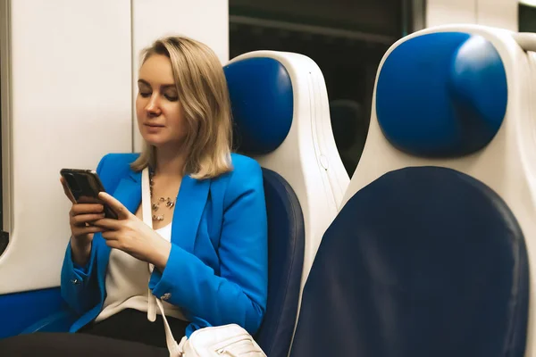 Woman in business suit with phone travelling by the train.