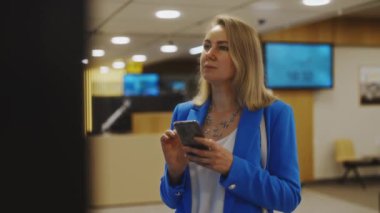Woman in business suit in checking her flight in airport.