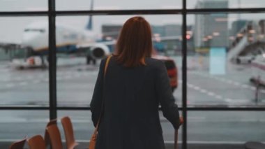 Woman with suitcase walking in airport terminal.