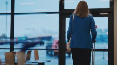 Woman with suitcase walking in airport terminal.