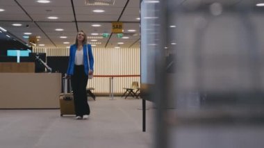 Woman with suitcase walking in airport terminal.