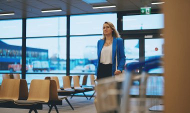 Woman with suitcase walking in airport terminal.
