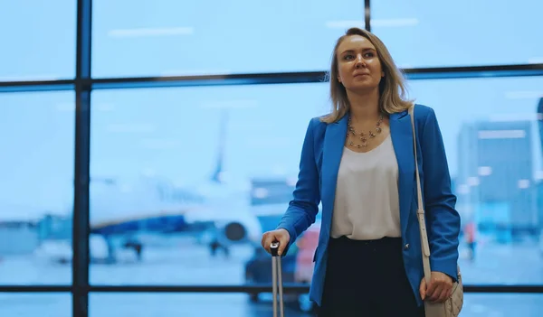 Woman in business suit is waiting for her departure at the airport.