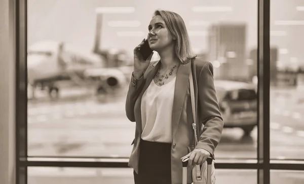 Woman in business suit is waiting for her departure at the airport.