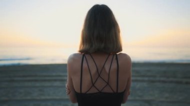 Mother cover his daughter with blanket and hugging on the beach at sunset.