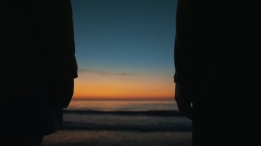 Couple in love holds hands at sunset by the sea.