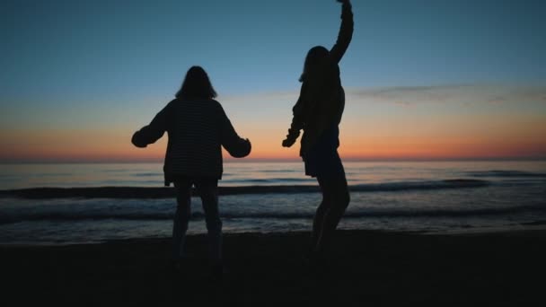 Dwie Dziewczyny Tańczą Wieczorem Zachodzie Słońca Nad Morzem — Wideo stockowe