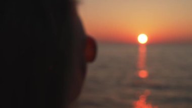 Female hands making heart shape in the sunset.