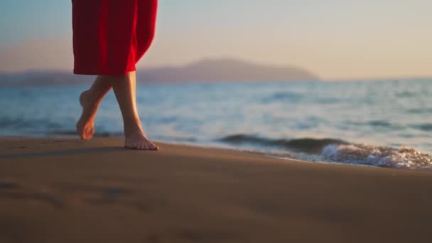 赤いドレスの女性がビーチ沿いを歩く — ストック動画