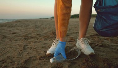 Kadın gönüllü sahilde çöp topluyor. Çevre kirliliği.