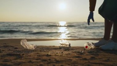 Kadın gönüllü sahilde çöp topluyor. Çevre kirliliği.