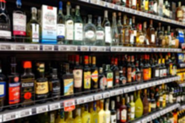 Raflar süpermarkette alkollü içecekler ile bulanık görüntü.