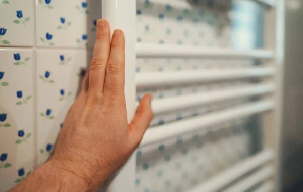 Man's hand checking temperature of heating radiator.