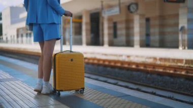 Woman with travel suitcase is waiting for a train.