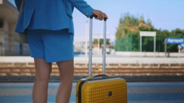 Woman with travel suitcase is waiting for a train.