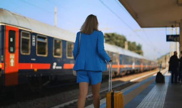 一个提着手提箱的女人沿着火车站的月台走着 — 图库照片