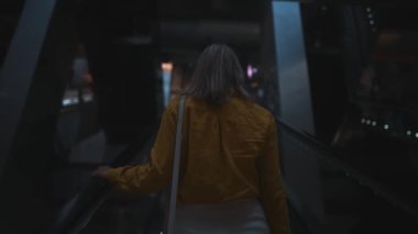 Metrodaki yürüyen merdiveni kullanan kadın..