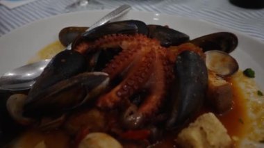 Domates sosunda pişirilmiş ahtapot, deniz mahsulü ve kızarmış ekmek..