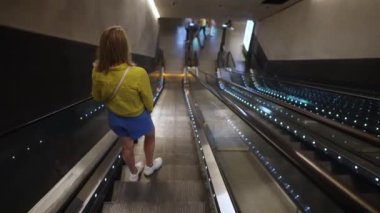 Metroda bir yürüyen merdiven kullanan kadın.