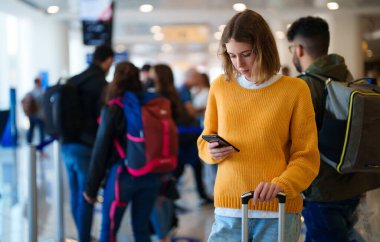 Teenage girl is waiting for her flight at the airport.