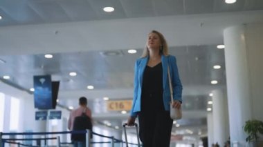 Woman with suitcase walking in airport terminal.