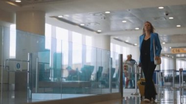 Woman with suitcase walking in airport terminal.