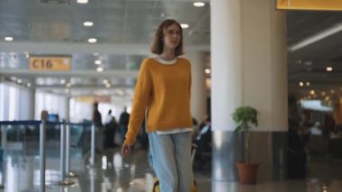 Tween girl with suitcase walking in airport terminal.