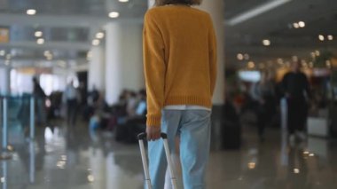 Tween girl with suitcase walking in airport terminal.