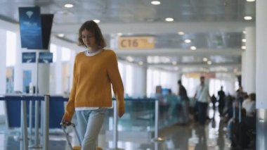 Tween girl with suitcase walking in airport terminal.