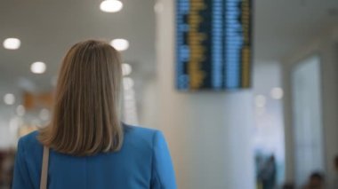 Woman in business suit in checking her flight in airport.