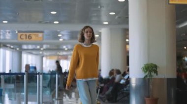 Tween girl with suitcase walking in airport terminal.