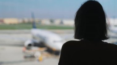 Teenage girl is waiting for her flight at the airport.