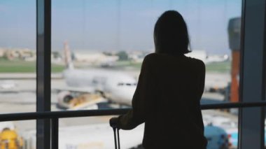Teenage girl is waiting for her flight at the airport.